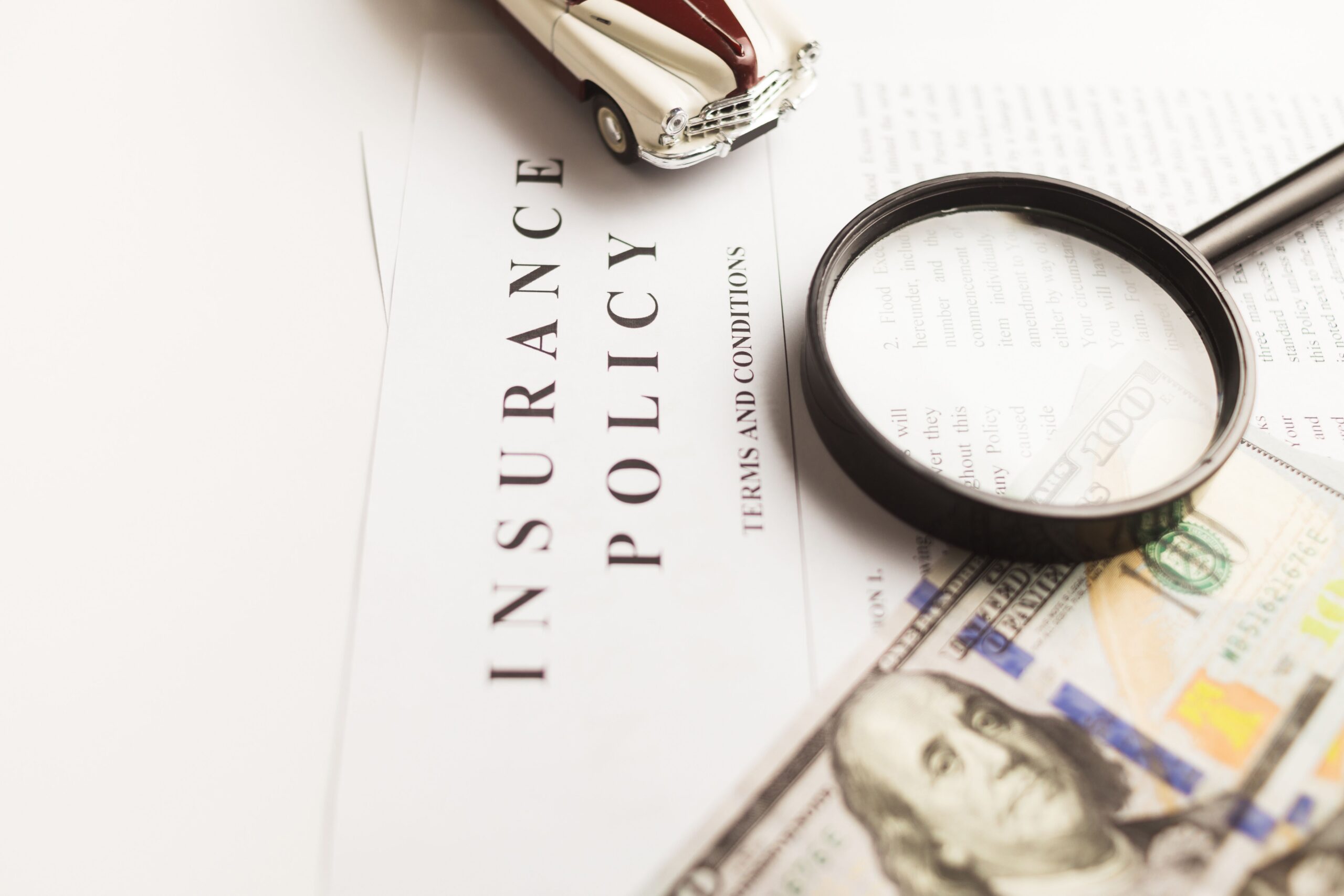 Auto insurance policy under a magnifying glass with a toy car, showing a review of uninsured motorist coverage limits