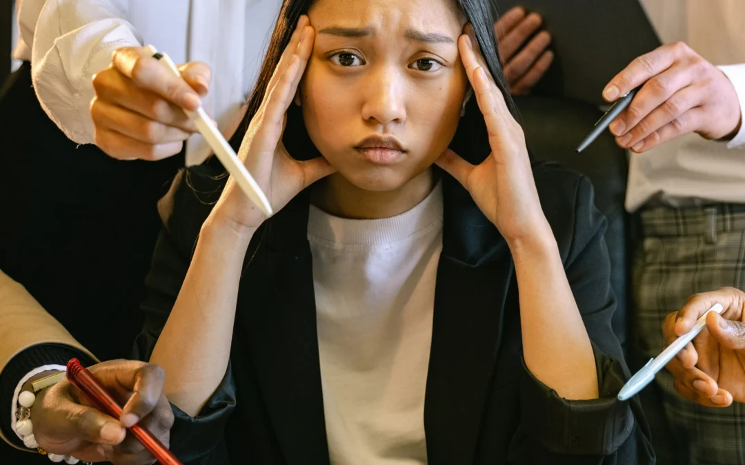 Stressed employee at her desk surrounded by coworkers, illustrating workplace harassment and retaliation in California